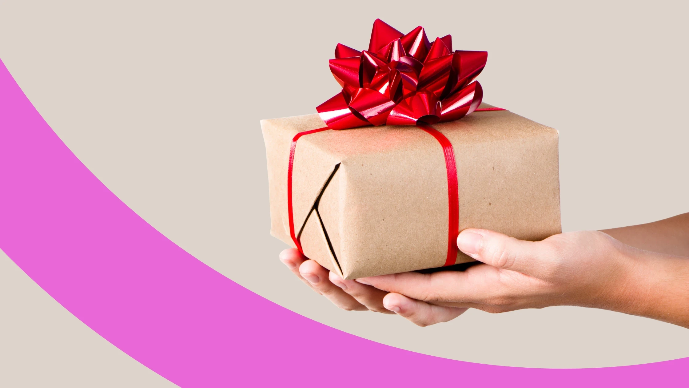 Zwei Hände halten ein in graues Geschenkpapier und einer roten Schleife verpacktes Weihnachtsgeschenk.