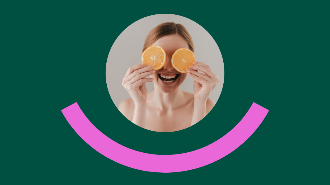 Eine lachende Frau hält zwei Orangenscheiben vor ihre Augen. Der Hintergrund ist dunkelgrün, unter dem Bild ist ein pinker, halbkreisförmiger Bogen wie ein stilisiertes Lächeln zu sehen.