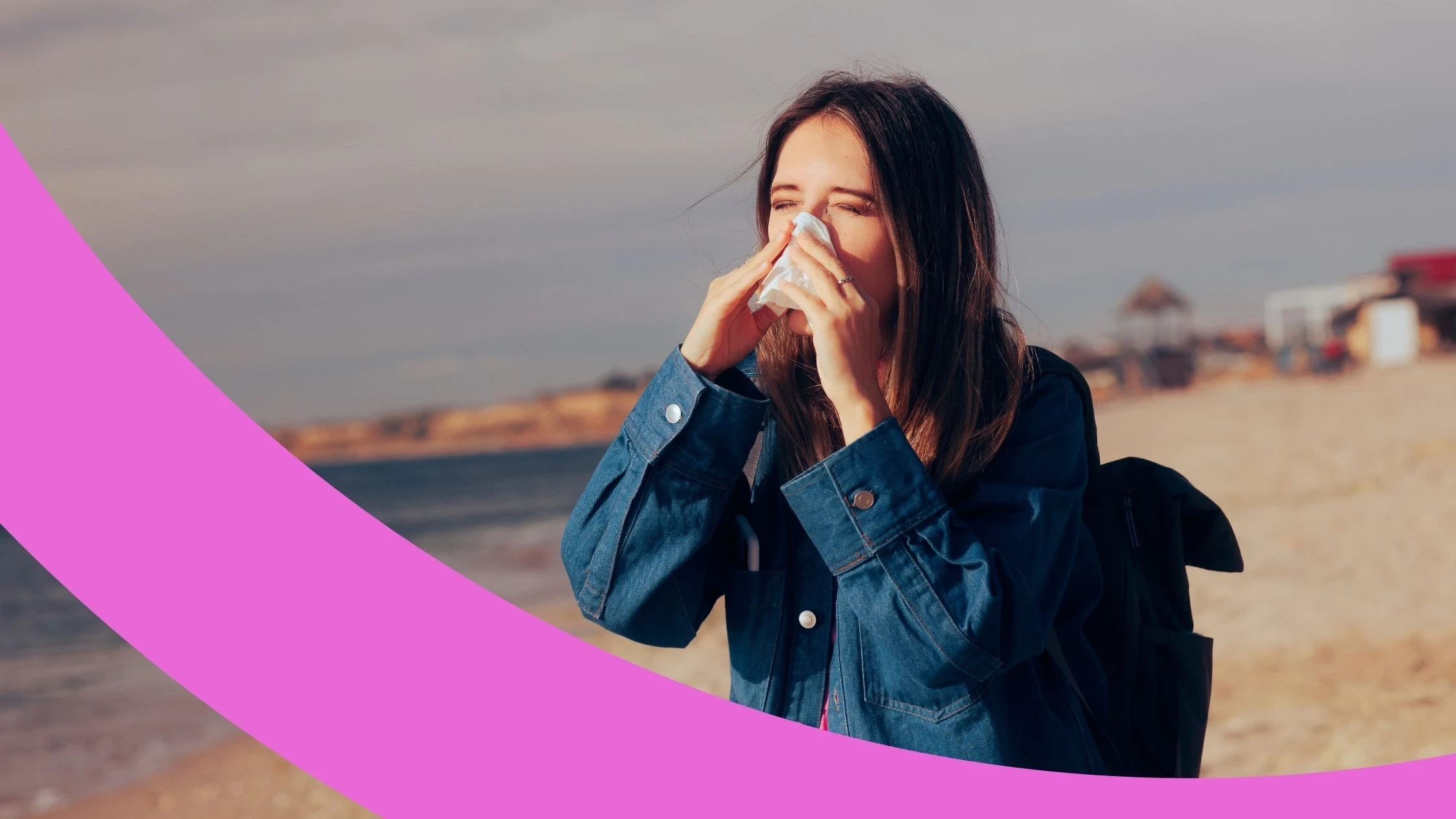 Frau steht am Strand und putzt sich die Nase.