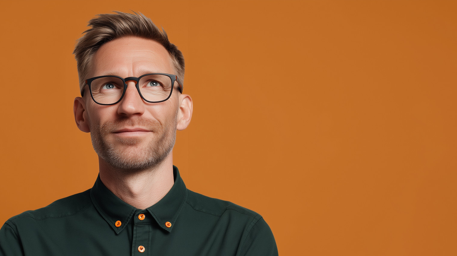 Arbeitgeber mit Brille in grünem Hemd vor orangefarbenem Hintergrund bei der Recherche nach bKV-Tarifen für sein Unternehmen.