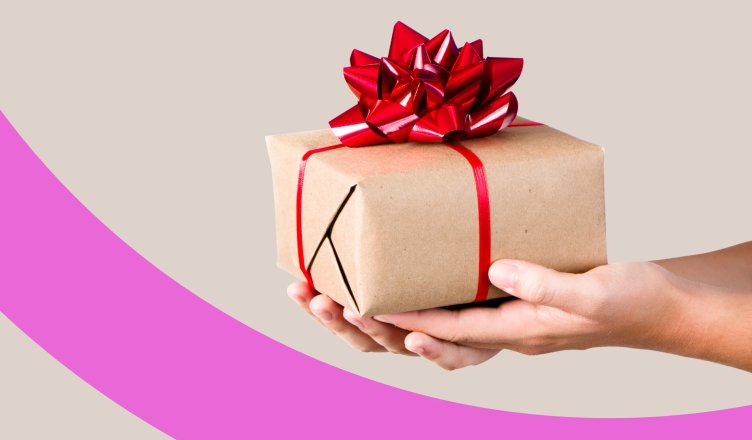 Zwei Hände halten ein in graues Geschenkpapier und einer roten Schleife verpacktes Weihnachtsgeschenk.