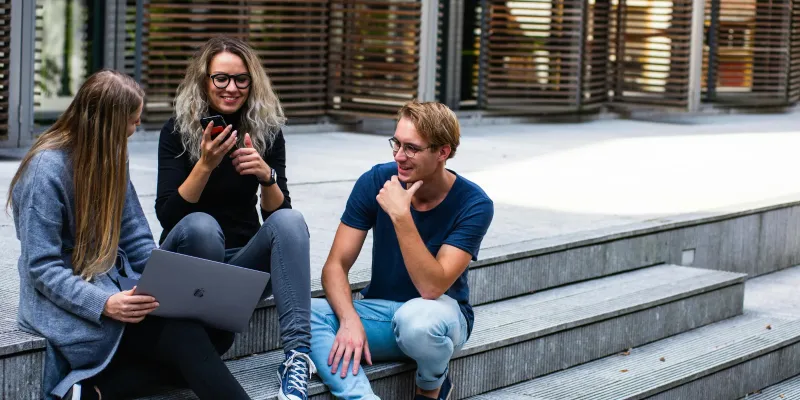 Drei Kollegen sitzen auf einer Treppe und unterhalten sich.