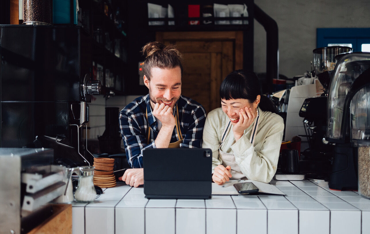 Zwei Kollegen im Café schauen gemeinsam auf das Gesundheitsbudget in der ofelos App