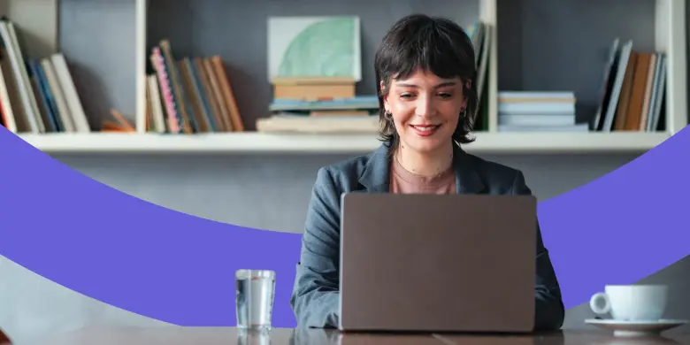 Frau sitzt an einem Tisch und arbeitet an ihrem Laptop.