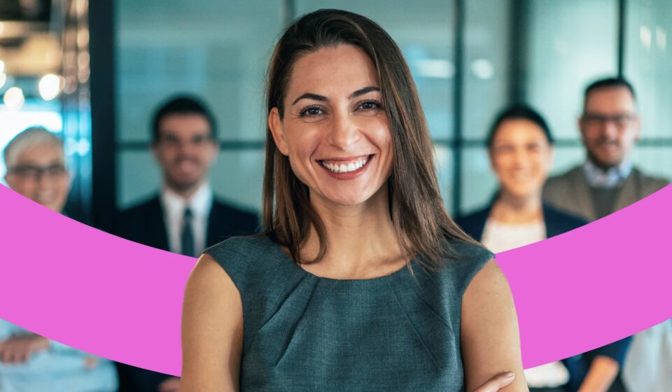 Lächelnde Mitarbeiterin steht mit vier Kollegen im Hintergrund.