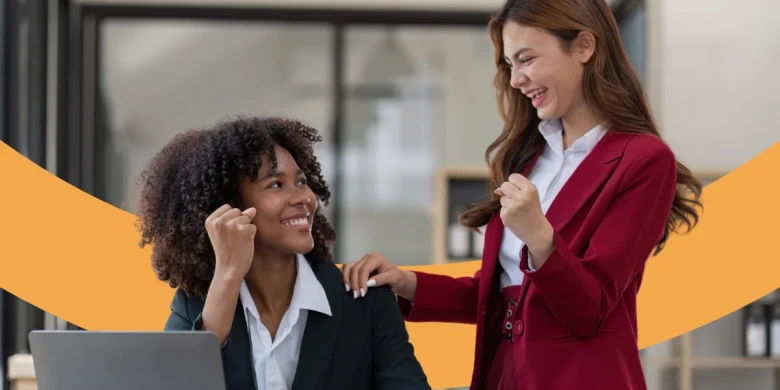 Zwei Mitarbeiterinnen freuen sich und lächeln sich an.