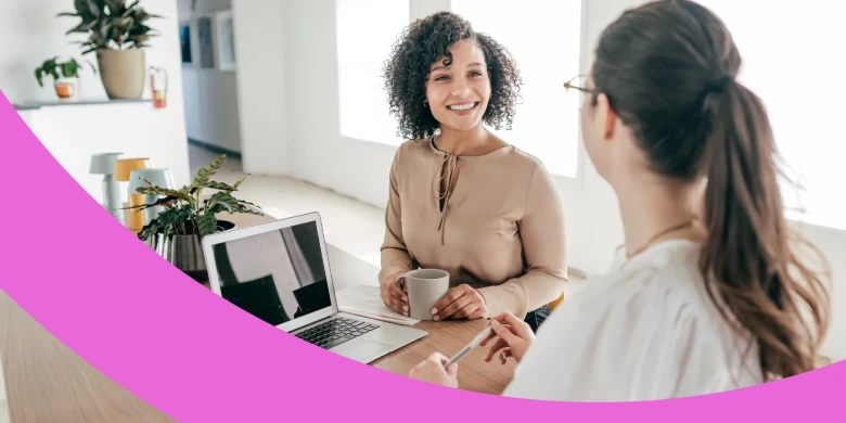 Zwei glückliche Mitarbeiterinnen unterhalten sich miteinander.