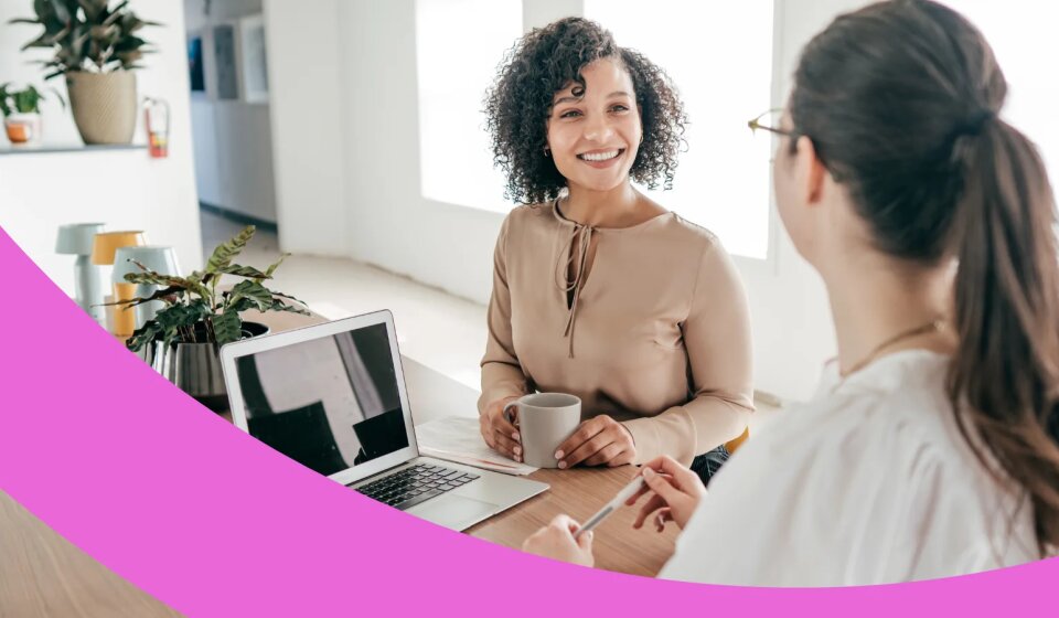 Zwei glückliche Mitarbeiterinnen unterhalten sich miteinander.