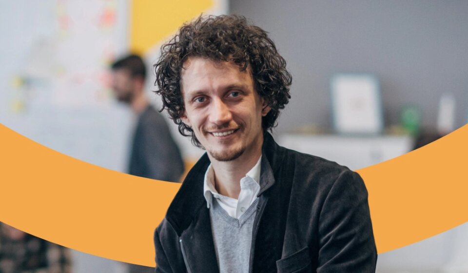 Sitzender Mann lächelt freundlich.