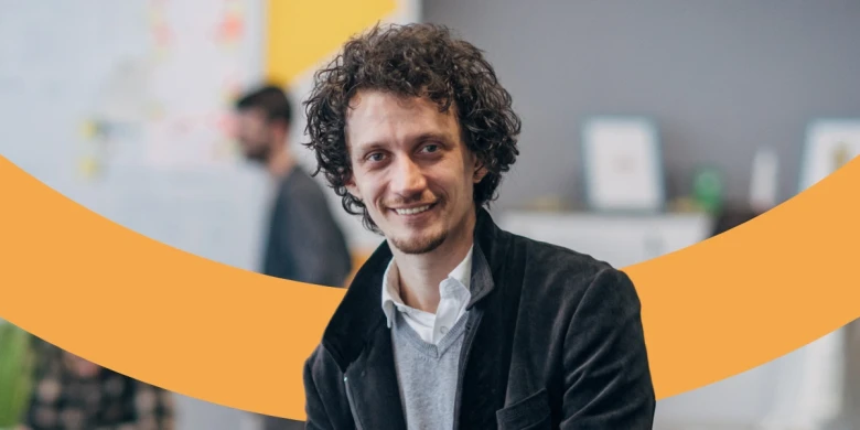 Sitzender Mann lächelt freundlich.