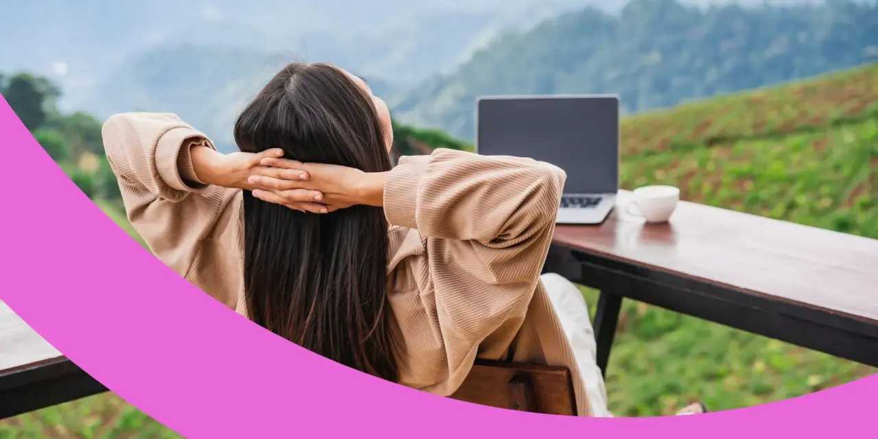 Frau sitzt entspannt mit Blick auf eine Berglandschaft vor ihrem Laptop.