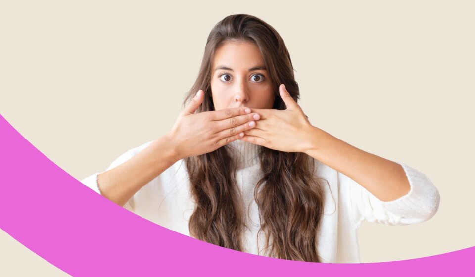 Frau verdeckt ihren Mund mit beiden Händen.